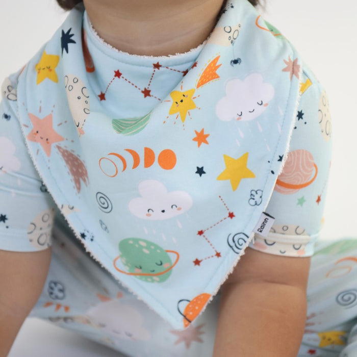 Child wearing Cosmic Bandana Dribble Bib featuring colorful space-themed prints by Rainn, perfect for drooling babies.