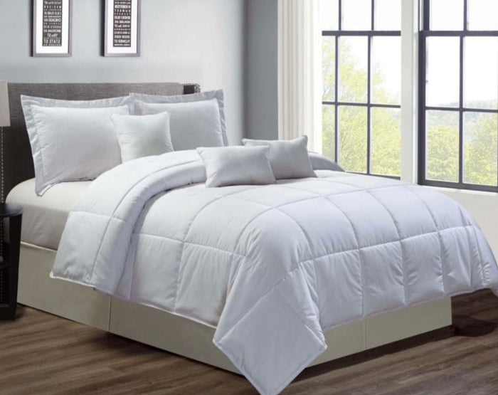 White comforter set on a bed in a room with large windows.