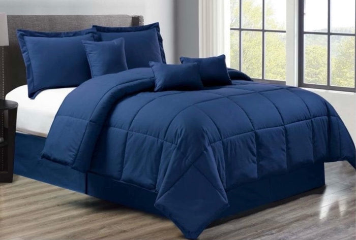 Blue comforter set on a bed in a room with large windows.