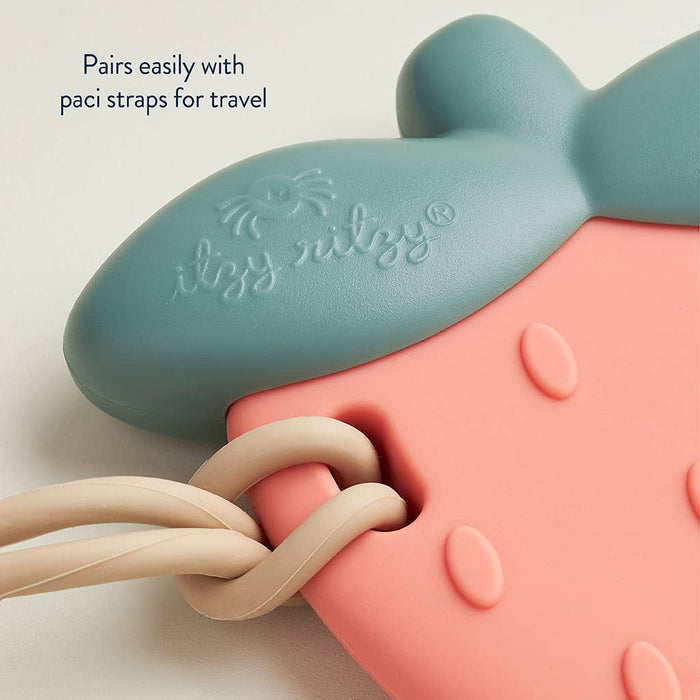 Close-up of Slicone Teething Rattle Strawberry Sweetie Shake™, showing blue and pink silicone with paci strap compatibility.