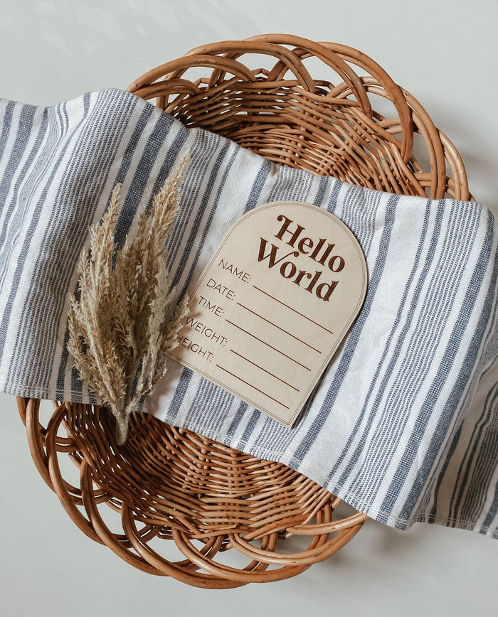 Modern arched wooden birth announcement plaque on striped fabric, perfect for recording baby info.